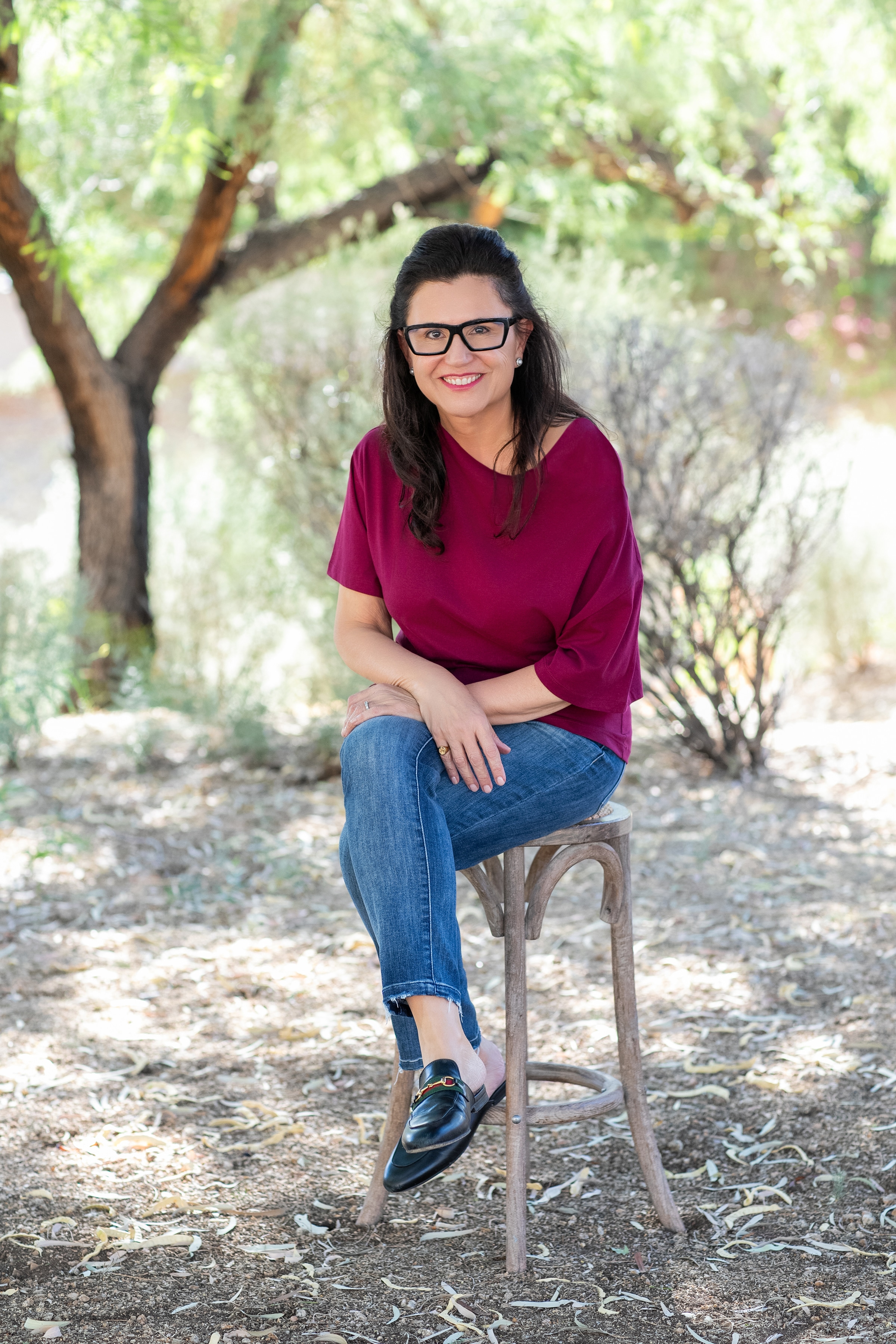 Ana Benitez seated outdoors beneath leafy desert trees.